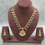 Traditional necklace with green stones, floral pendant, and pearl drops