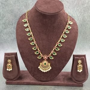 Traditional necklace with green stones, floral pendant, and pearl drops
