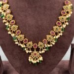 Designer necklace featuring floral and rectangular motifs with green and pink stones