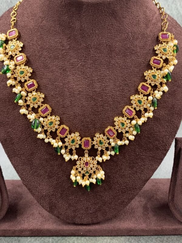 Designer necklace featuring floral and rectangular motifs with green and pink stones