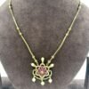 Elegant gold necklace featuring floral pendant with pink stones and pearl drops displayed on gray jewelry stand