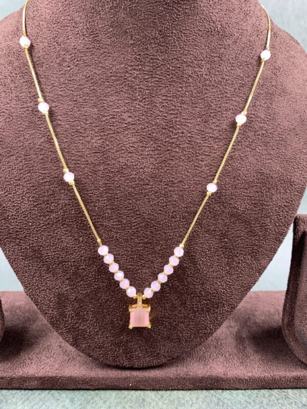 nvisible chain necklace featuring a pink rectangular stone and delicate white beads