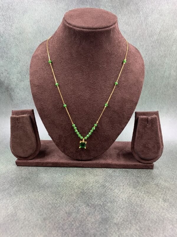 Invisible chain necklace featuring a green rectangular stone and delicate white beads