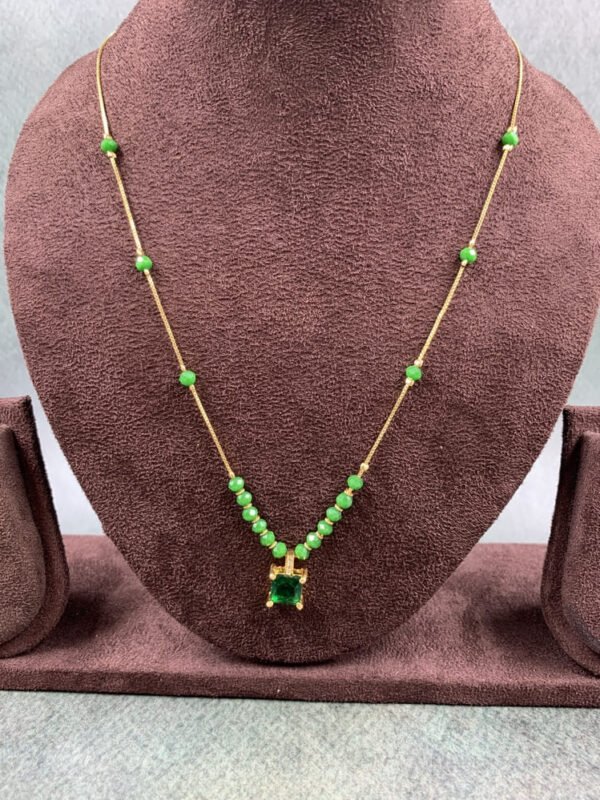 Invisible chain necklace featuring a green rectangular stone and delicate white beads
